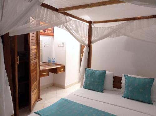 a bedroom with a bed with blue pillows and a desk at Pendo Villas Diani Beach in Diani Beach