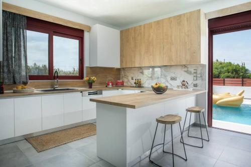 a kitchen with white cabinets and a counter with stools at SunDaLucky in Afantou