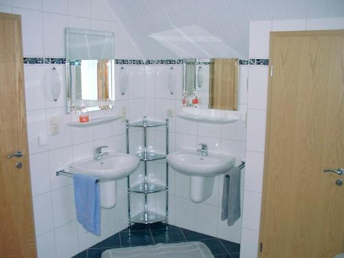 ein Badezimmer mit zwei Waschbecken und zwei Spiegeln in der Unterkunft Ferienwohnung Gebken in Börgerwald