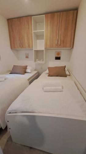 2 camas en una habitación con armarios de madera en Premium mobile home Maslina - Oaza mira, en Drage