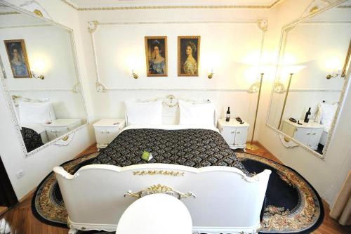 a bedroom with a white bed and two mirrors at Queen's Astoria Design Hotel in Belgrade