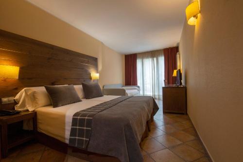 a hotel room with a large bed with a wooden headboard at Hotel Màgic Ski in La Massana