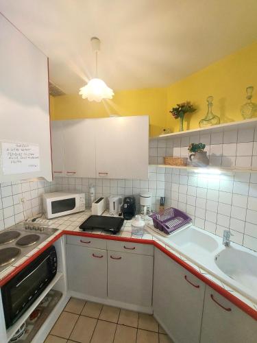 une cuisine avec des armoires blanches, un évier et un micro-ondes dans l'établissement soleil catalan ok chéques vacances animaux rdc 150m mer 4pers wifi 2ch, à Saint-Cyprien