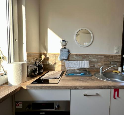- un comptoir de cuisine avec un évier et un miroir dans l'établissement Domek przy plaży, à Rewa