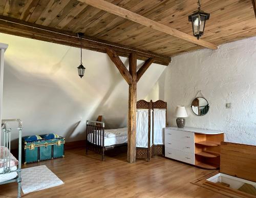 a bedroom with a crib in a room with wooden ceilings at Domek przy plaży in Rewa