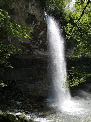 a waterfall in a river with a person standing under it at Ecolodge, bain nordique, petit dejeuner in Fort-du-Plasne