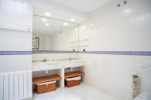 a white bathroom with a sink and a mirror at Casa Cala Balmins in Sitges