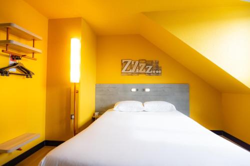 a bedroom with a large bed with yellow walls at ibis budget Besançon Centre Gare in Besançon