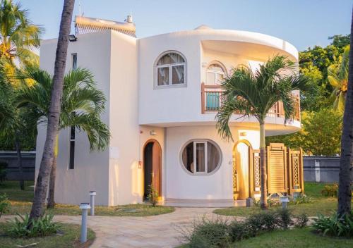 a white house with palm trees in front of it at Gold Beach Resort in Flic-en-Flac