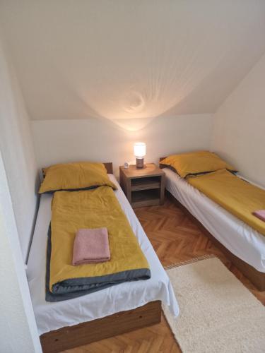 Habitación pequeña con 2 camas individuales y mesa. en reginavendeghaz en Balatonmáriafürdő