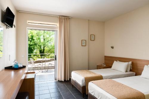 a hotel room with two beds and a balcony at Gefiri Plakas Hotel by Konnect, Tzoumerka in Plaka