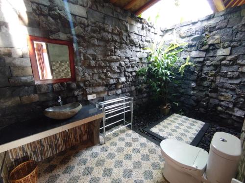 een stenen badkamer met een wastafel en een toilet bij Abian view house in Sidemen