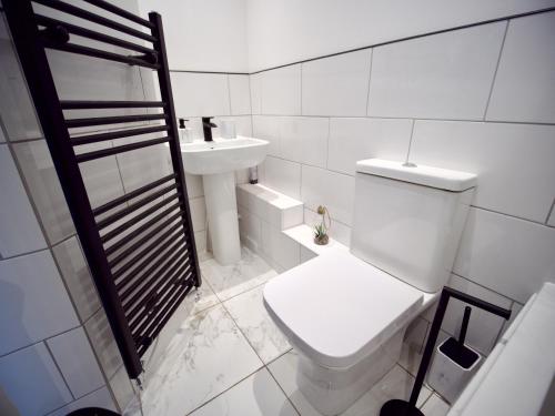 Ideal Lodgings in Radcliffe في رادكليف: حمام ابيض مع مرحاض ومغسلة