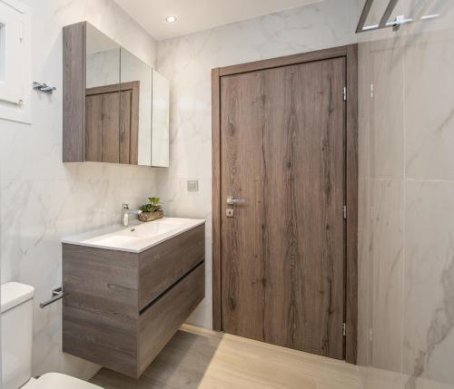 a bathroom with a sink and a wooden door at Hypatia Suites in Zakynthos Town