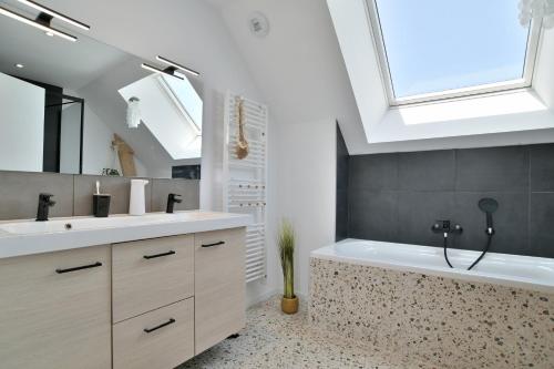 baño con lavabo, bañera y ventana en Maison Gwenan - Maison contemporaine pour 8 proche plage, en Saint-Cast-le-Guildo