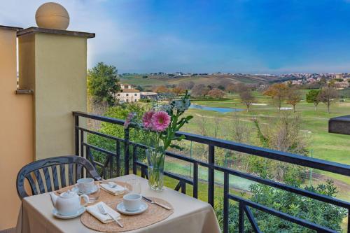 a table with a vase of flowers on a balcony at Carpediem Roma Golf Club in Marco Simone