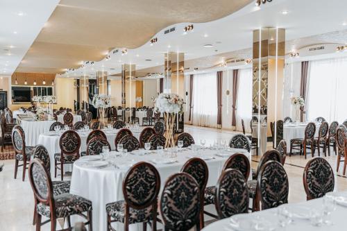 un salón de banquetes con mesas y sillas blancas en Hotel Bliss en Sibiu