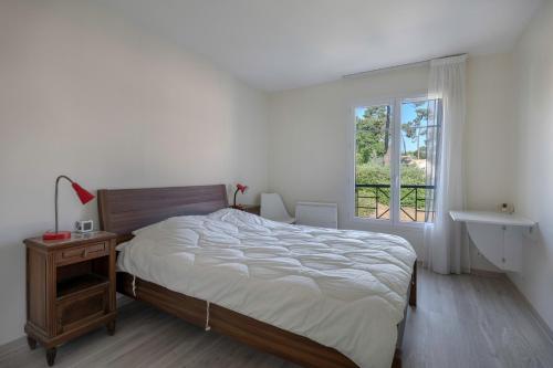 ein weißes Schlafzimmer mit einem Bett und einem Fenster in der Unterkunft Maison à 500m de la plage pour 4 in Saint-Brévin-lʼOcéan