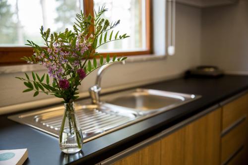 a vase with purple flowers sitting next to a sink at May Villas in Ordu