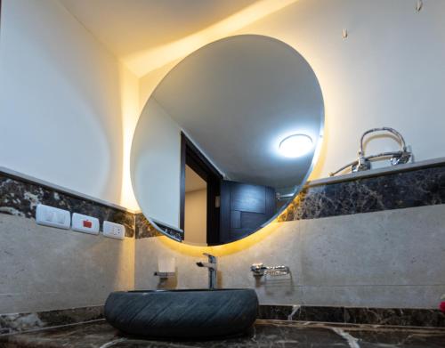 a bathroom with a large round mirror and a sink at marron studios 4 new in Cairo