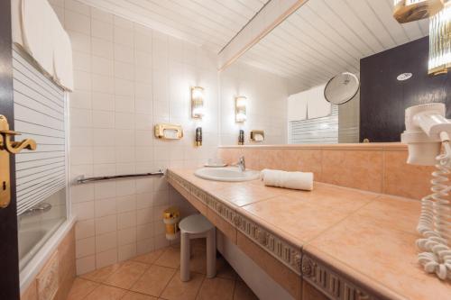 W łazience znajduje się umywalka, wanna i lustro. w obiekcie Hotel Pfeifer w mieście Gaschurn