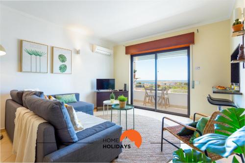 a living room with a couch and a balcony at #005 Foxy B by Home Holidays in Caliços