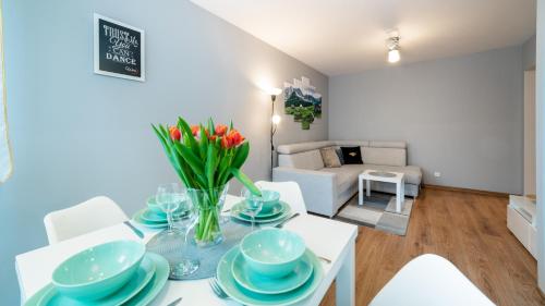 een woonkamer met een tafel met een vaas met bloemen erop bij Apartament Szept Lasu - z prywatnym parkingiem - Space Apart in Karpacz