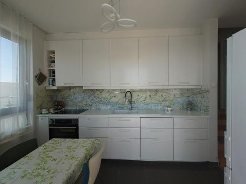una cocina con armarios blancos y fregadero en Apartment Summerhill, en Primošten