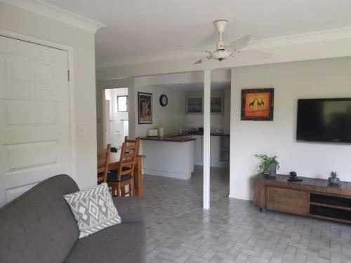 a living room with a couch and a tv and a kitchen at Rural Escape in Boambee