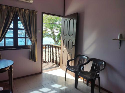 two black chairs in a room with a balcony at Horizon Inn in Kampung Teluk Nipah