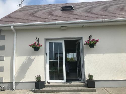 a white house with two flower pots on the door at Loch Nuala in Galway