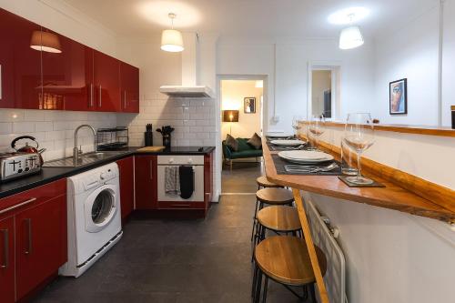 una cocina con armarios rojos y una barra con copas de vino en Trendy 2Bed flat Bethnal Green, en Londres