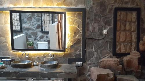 Baño de piedra con 2 lavabos y espejo en Valhalla Bed & Breakfast en Salatiga