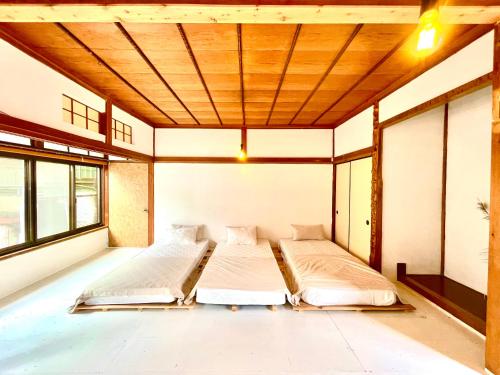 two beds in a large room with windows at 三丁庵ゲストハウス 紫陽花祭り会場まですぐ 観光地ペリーロードまですぐの最高なロケーション 下田を遊び尽くせるゲストハウス 無料駐車場もありますJapanese old style guest house that close to Perry road We have long stay plan in Harada