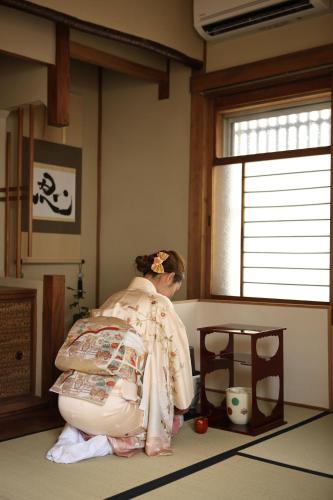 a woman in a kimono kneeling in a room at 帝塚山忍者屋敷 in Osaka
