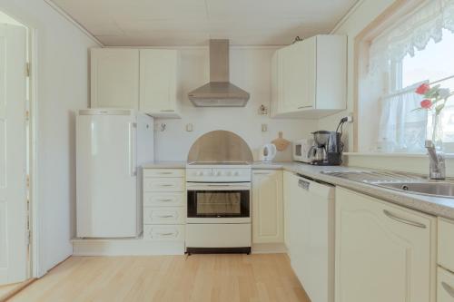 a white kitchen with white cabinets and a sink at Sea and Mountain View - Scenic Village - 2BR House in Viðareiði