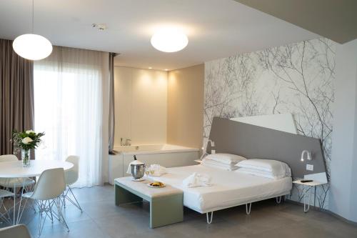 1 dormitorio con cama blanca, mesa y mesa en Hotel Malavoglia en Acitrezza