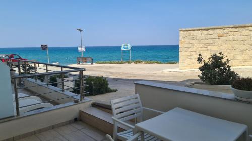 a balcony with a table and chairs and the beach at Bella Mare Luxury Apartments in Kalamaki Heraklion