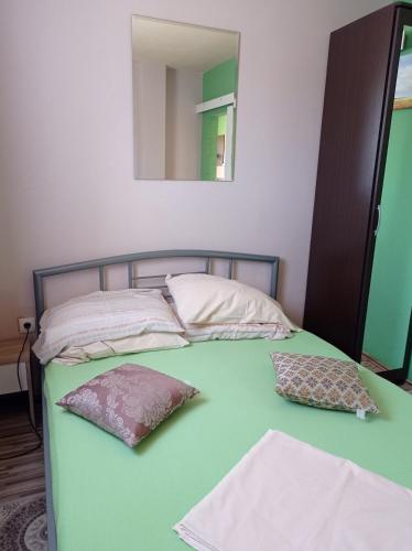 uma cama verde com duas almofadas e um espelho em Panorama Apartments em Skradin