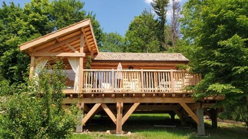 a large wooden cabin with a deck in the grass at La Cabane du Domaine des Ecus d'Or in La Bussière-sur-Ouche