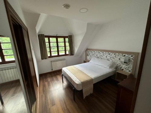 a small bedroom with a bed and two windows at Hello Astur Green in Bimenes