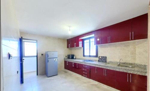 a kitchen with red cabinets and a refrigerator at KHALIJ HOSPITALITE in Dakhla