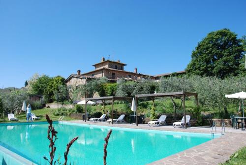 a swimming pool with chairs and umbrellas next to a building at Poggio Alle Lame in Tavarnelle in Val di Pesa