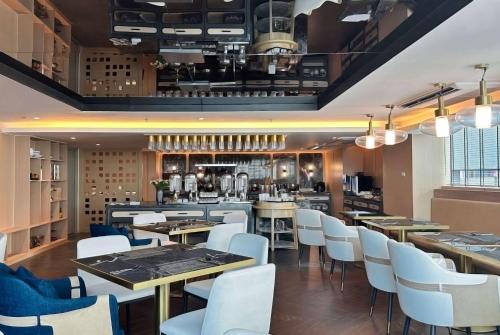 a restaurant with wooden tables and white chairs at Ramada Sukhumvit Soi Eleven in Bangkok