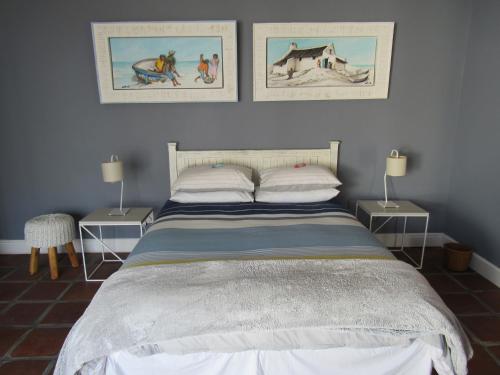 a bedroom with a bed with two tables and two pictures on the wall at Omega Suite in Gansbaai