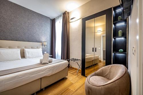 a bedroom with a bed and a chair and a mirror at Martelli 6 Suite & Apartments in Florence
