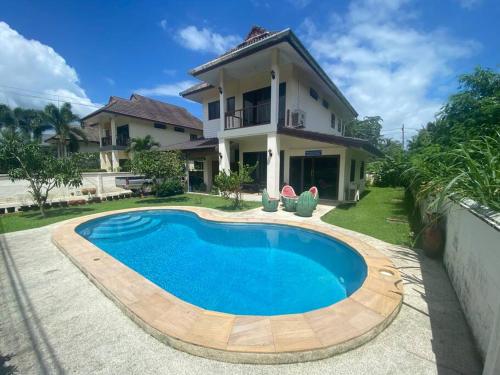 a swimming pool in front of a house at Thai style 3 bedroom pool house. in Khao Lak