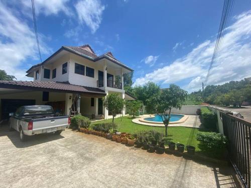a house with a truck parked in the driveway at Thai style 3 bedroom pool house. in Khao Lak