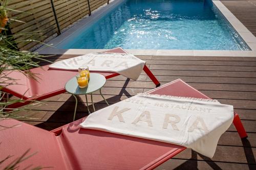 - une piscine avec 2 chaises et une table avec une serviette dans l'établissement Brit Hotel Kara Sainte Anne d'Auray, à Sainte-Anne-d'Auray