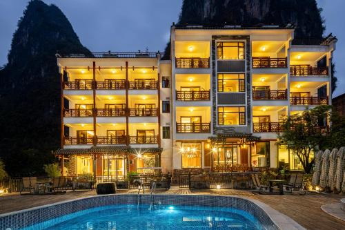 a hotel with a swimming pool in front of a building at Yangshuo Shanshuiyao Resort - Free Train Station Pick Up and Drop Off in Yangshuo